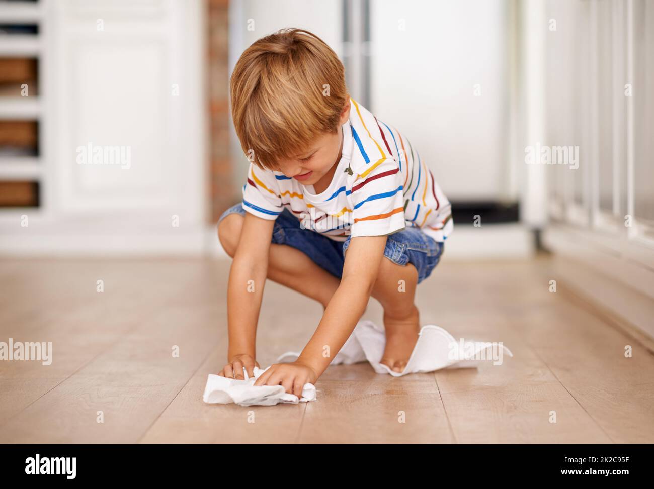 Pulizia dopo se stesso. Scatto di un ragazzino che gioca sul pavimento. Foto Stock