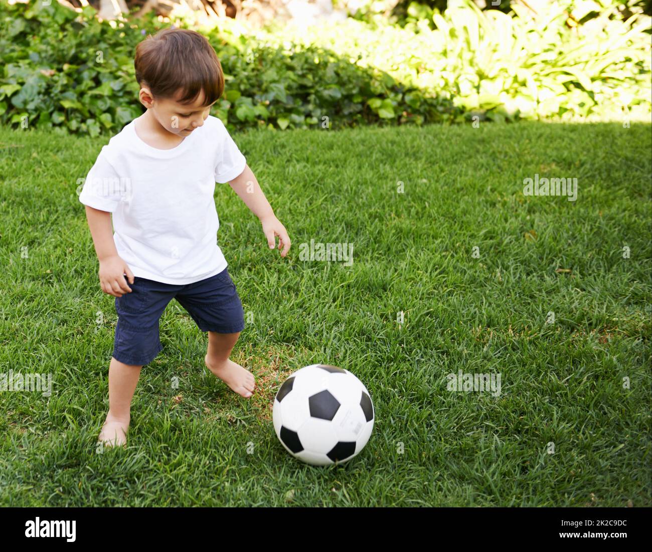 Calcio nel cortile. Un ragazzino dolce con una palla da calcio nel cortile. Foto Stock