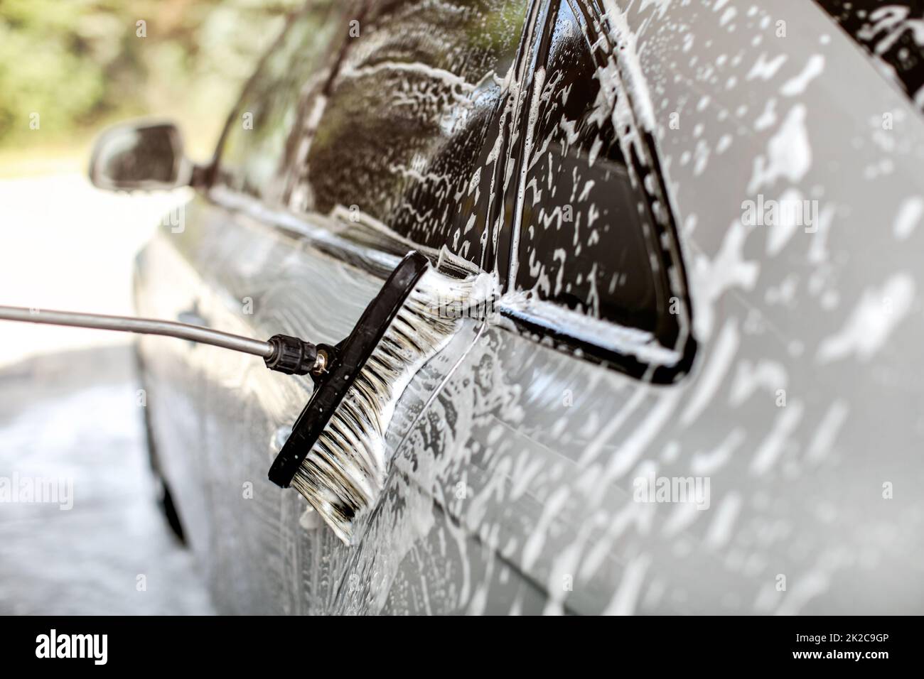 Lato di argento auto lavata in self service autolavaggi, spazzola lasciando tratti in shampoo e schiuma. Foto Stock