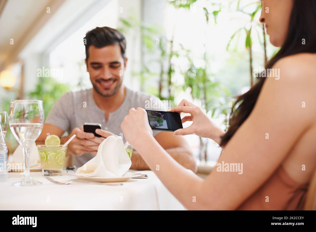 Ricordi romantici. Una donna che fa una foto mentre cena fuori con il suo partner in un ristorante. Foto Stock