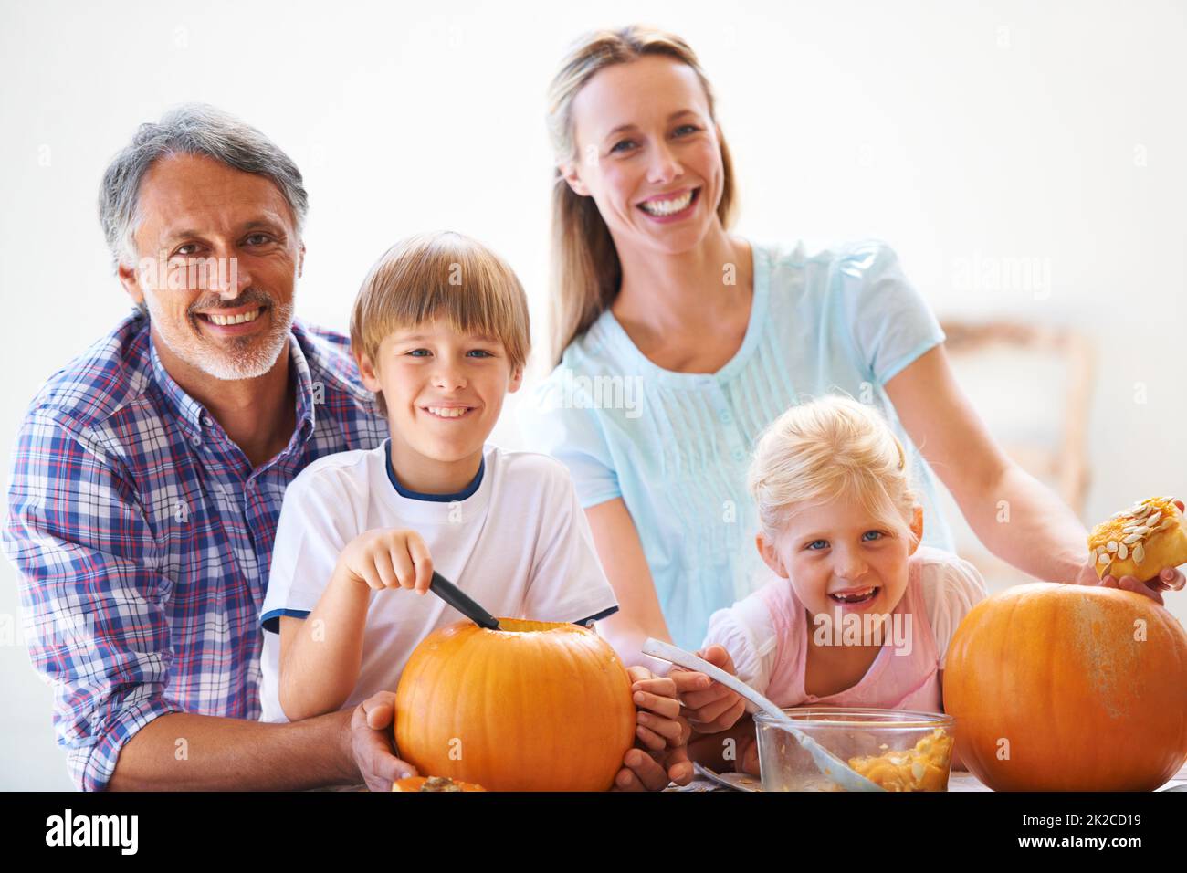 Tradizioni familiari. Ritratto di una famiglia di quattro hollowing fuori zucche per Halloween. Foto Stock