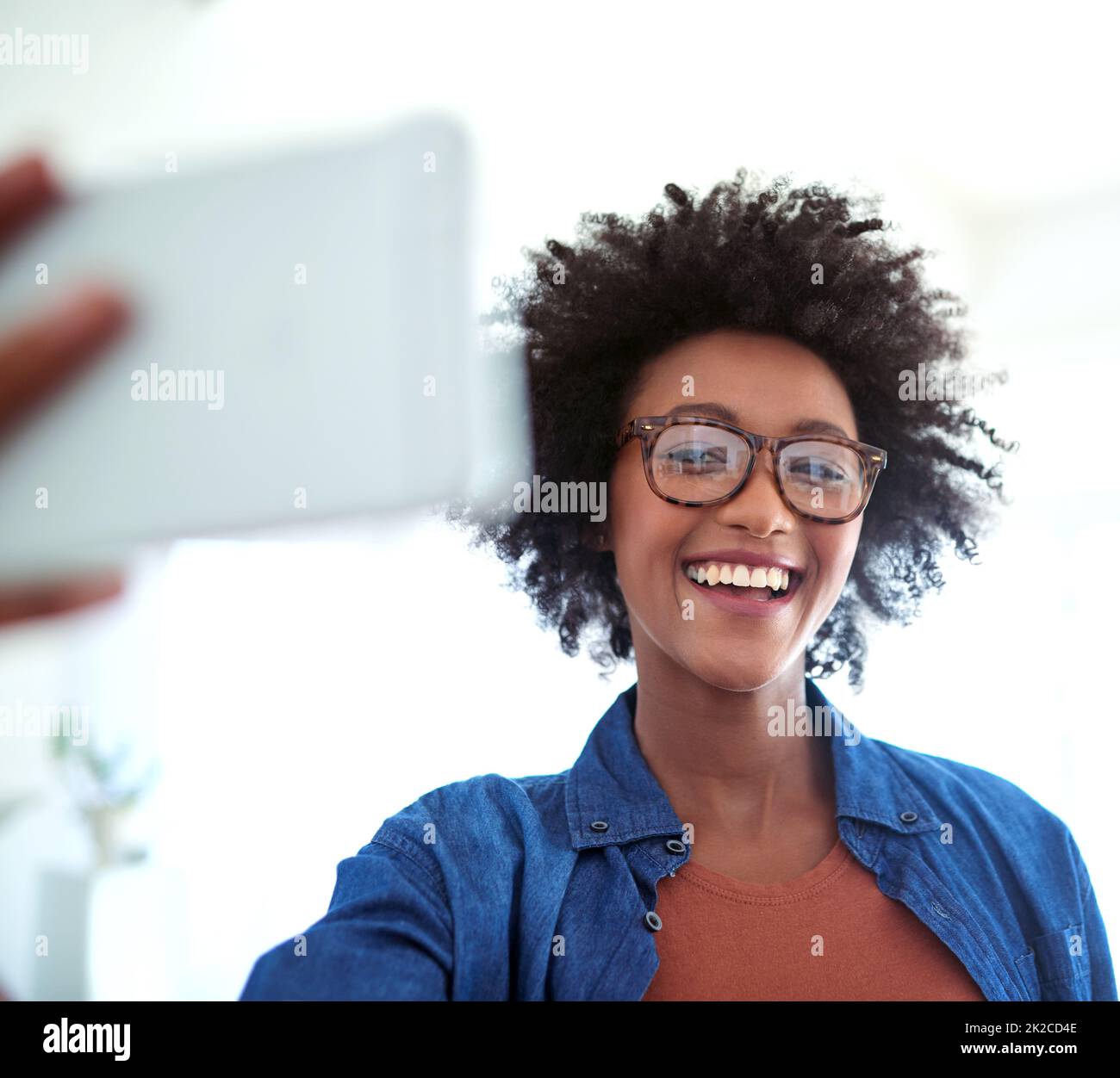 Sfruttando al massimo il suo tempo libero. Scatto di una giovane donna attraente che prende un selfie a casa. Foto Stock