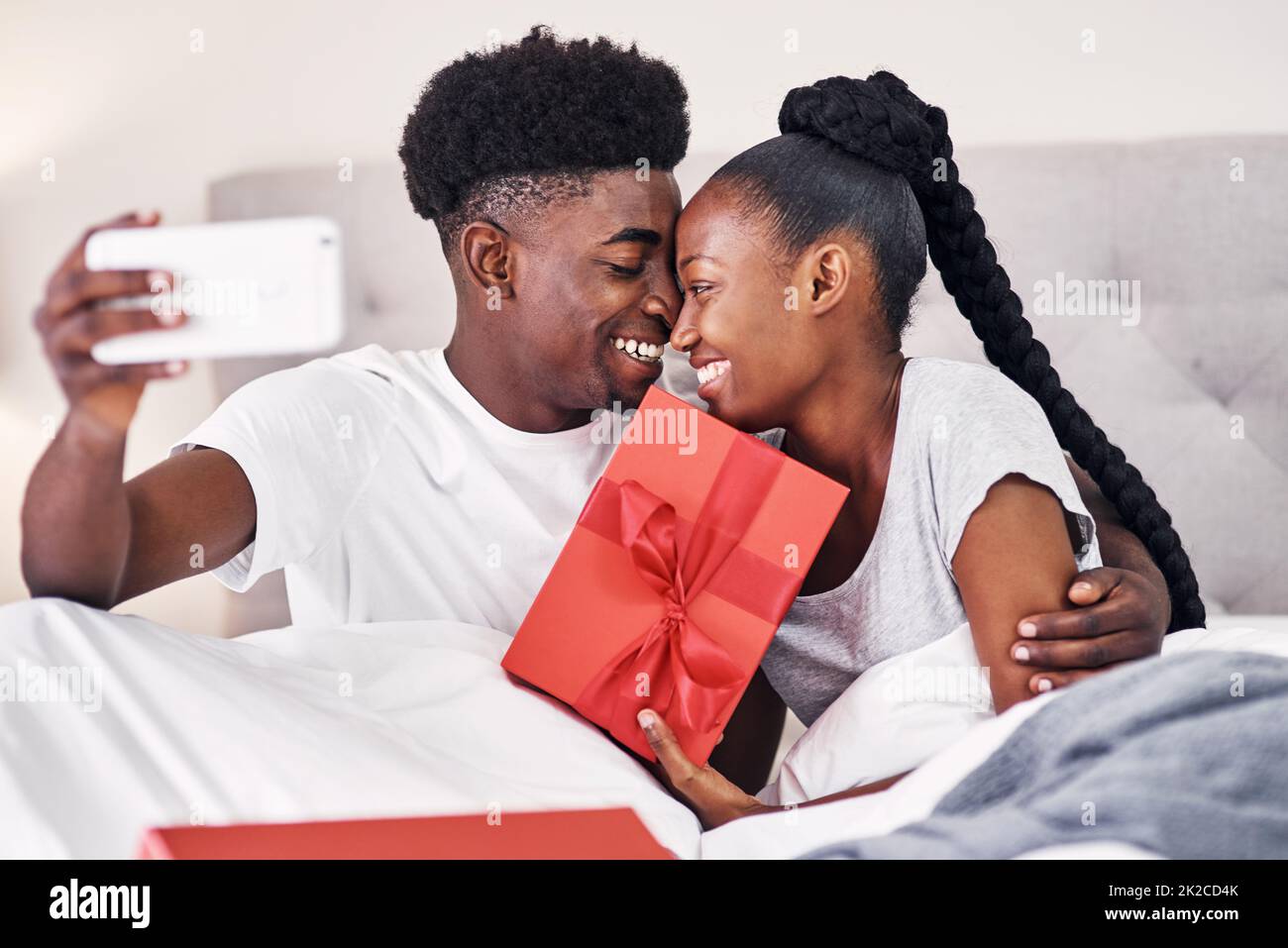 Voglio cogliere questo momento. Scatto di una giovane donna che tiene in mano una scatola regalo mentre prende un selfie con il suo ragazzo. Foto Stock