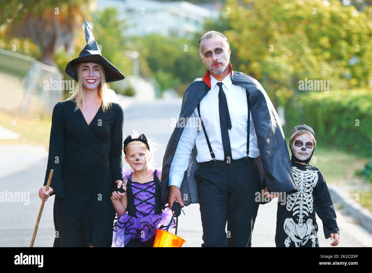 Festeggiamo il divertimento insieme. Una famiglia carina vestita per Halloween che camminano lungo la loro strada. Foto Stock