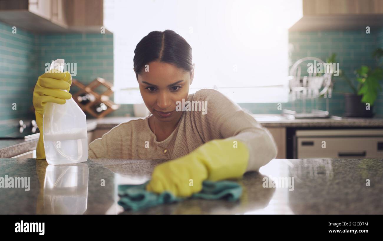 Devo andare in ogni posto. Colpo di una giovane donna che sfrega verso il basso il suo banco di cucina a casa. Foto Stock