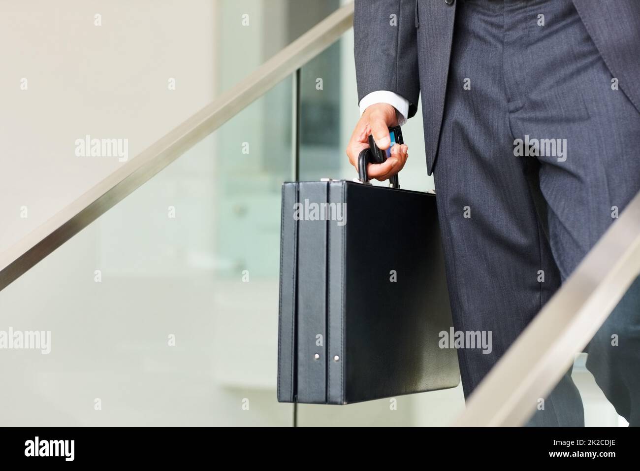 Uomo d'affari che trasporta un cellulare e una valigia. Sezione bassa di uomo d'affari che trasporta un cellulare e una valigia e che cammina giù le scale. Foto Stock
