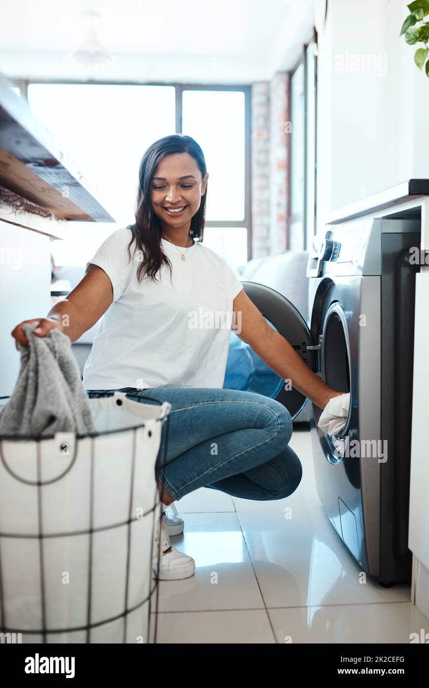 Ottenere il bucato fatto prima che si accumuli. Scatto di una giovane donna usando una lavatrice a casa. Foto Stock