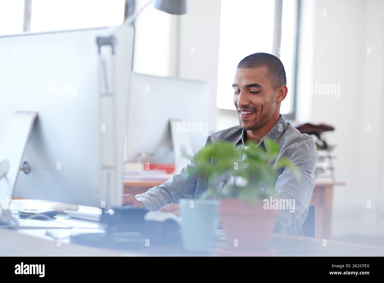 La mia professione mi ha fatto sentire bene. Giovane uomo multietnico al lavoro in un luminoso spazio d'ufficio. Foto Stock