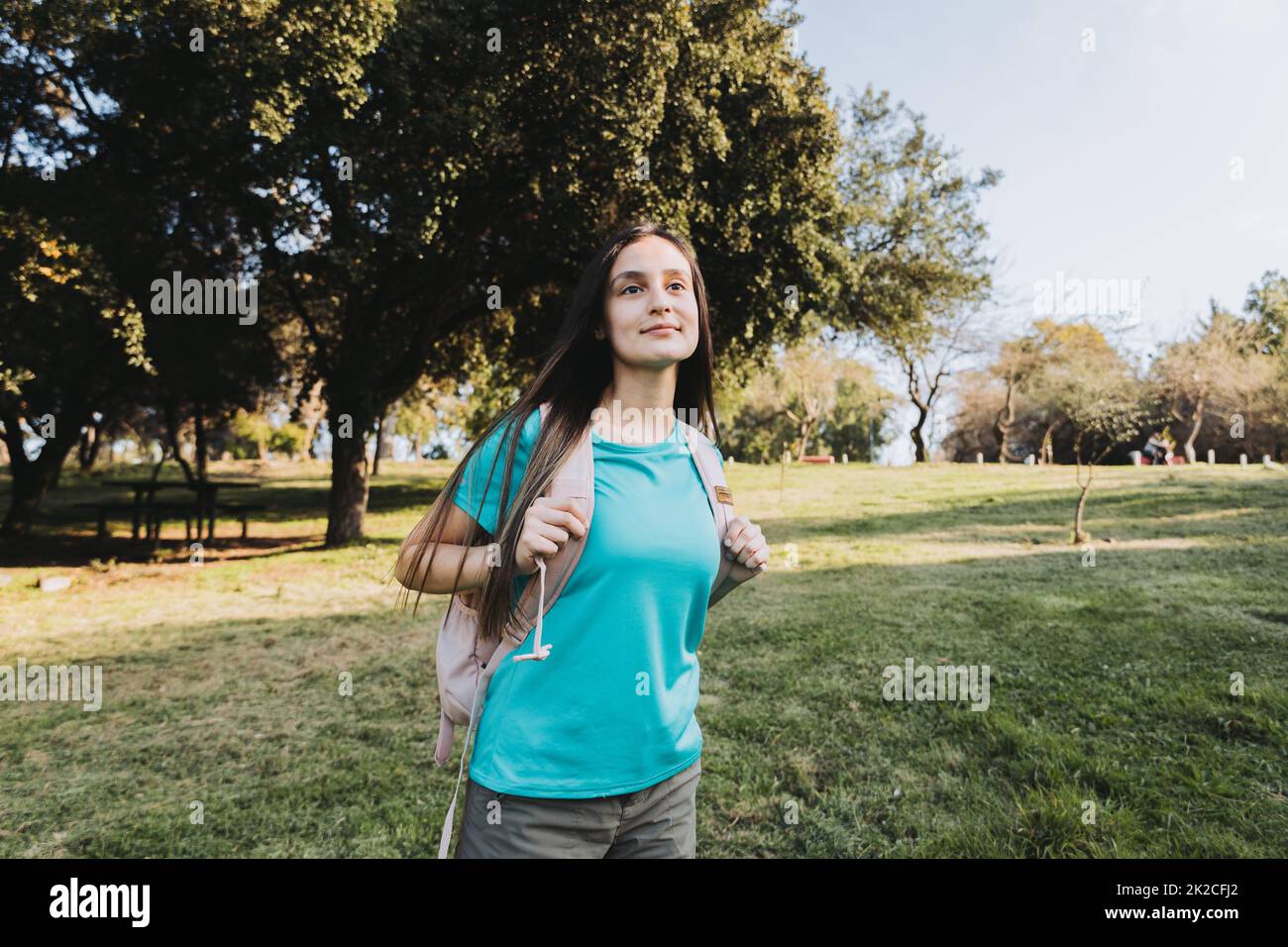 Guardando al futuro. Giovane studentessa universitaria che indossa la t shirt aquamarina guardando l'orizzonte nel campus. Foto Stock