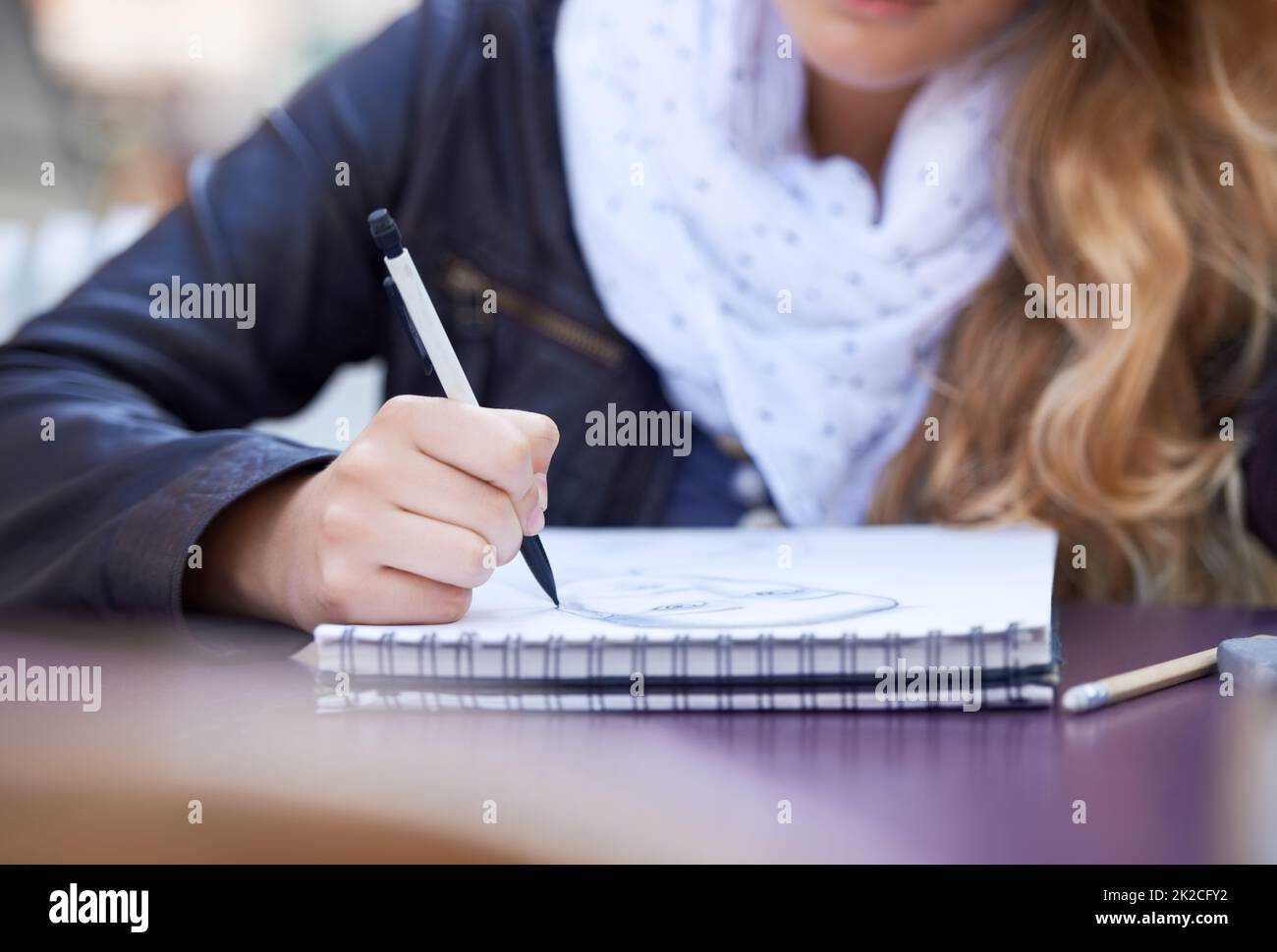 Disegnare nel suo tempo libero. Una giovane donna che attingeva nel suo blocco note. Foto Stock