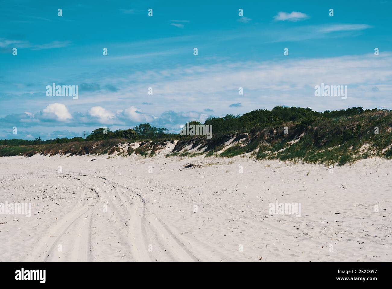 Dune, con erba in luoghi, piste auto sulla sabbia. Cielo blu con nuvole Foto Stock