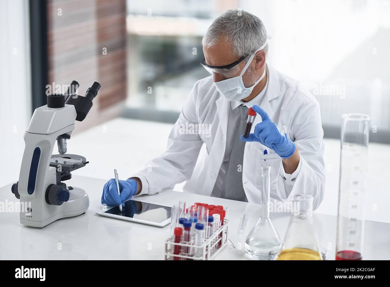 Prendere nota di un test utile. Scatto di un ricercatore al lavoro su un microscopio in un laboratorio. Foto Stock