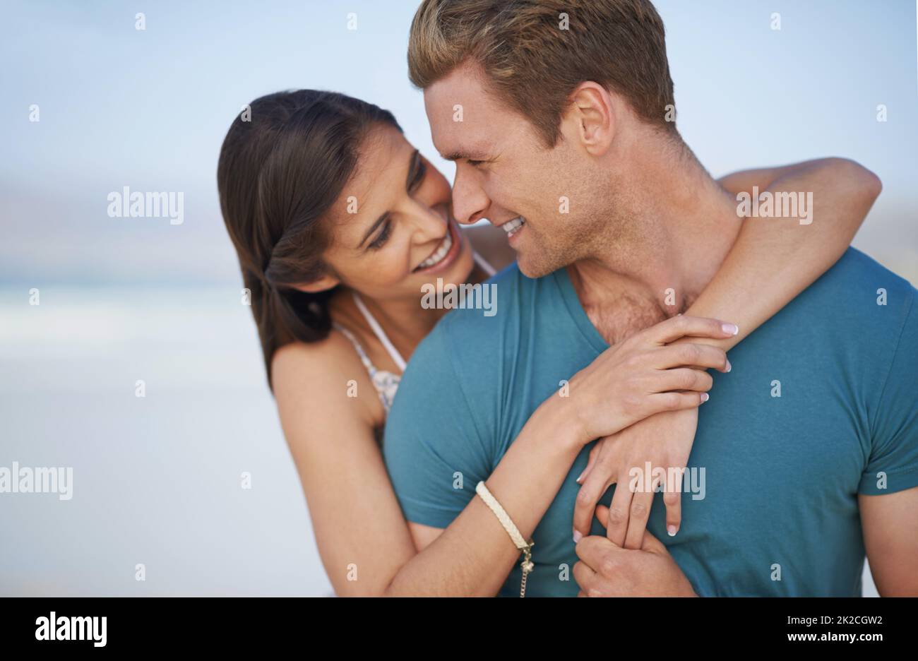 Il nostro amore è per sempre. Una giovane coppia che abbraccia felicemente la spiaggia. Foto Stock