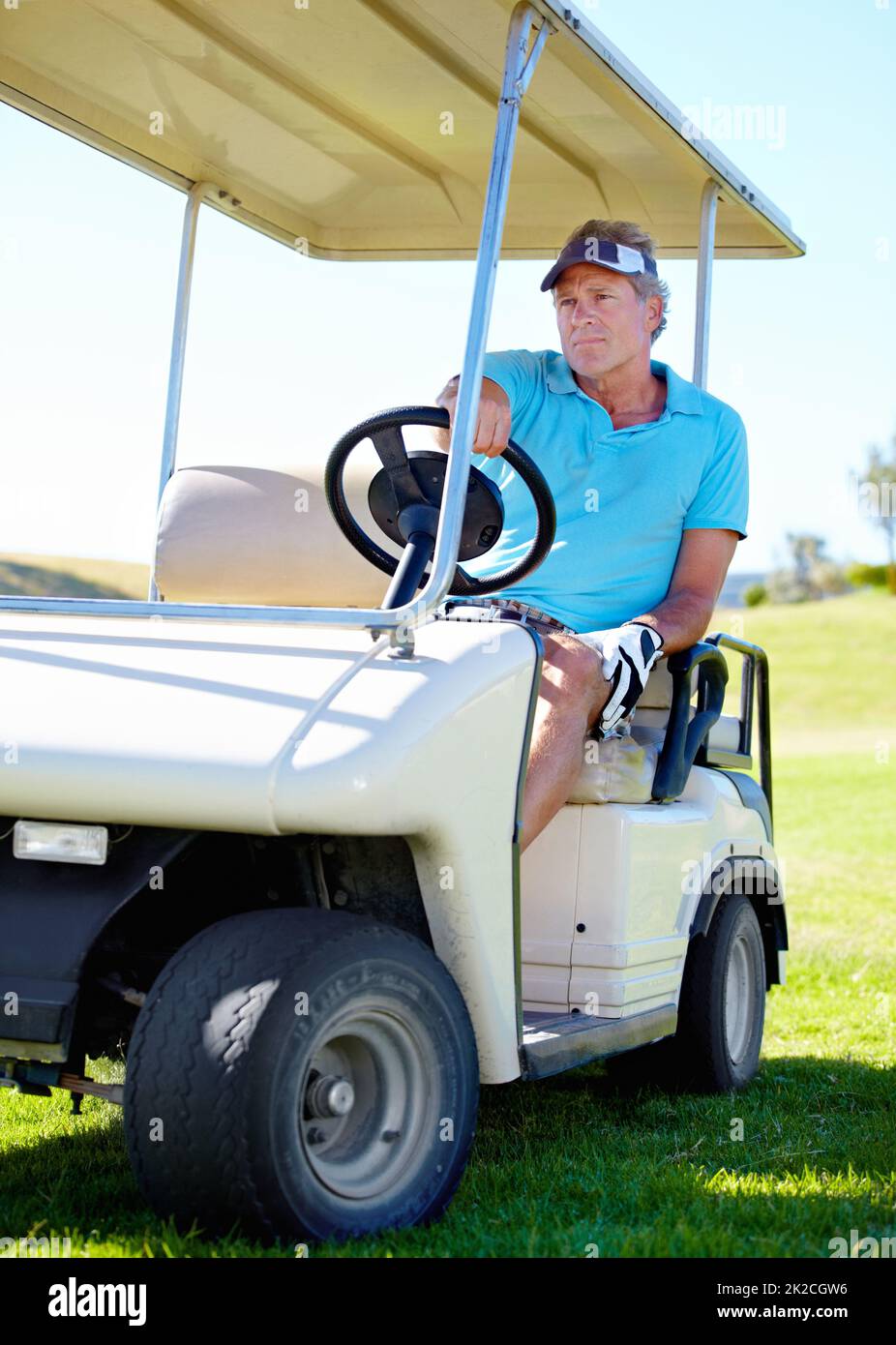 Golf i.. Un uomo maturo che guida un carrello sopra il campo da golf. Foto Stock