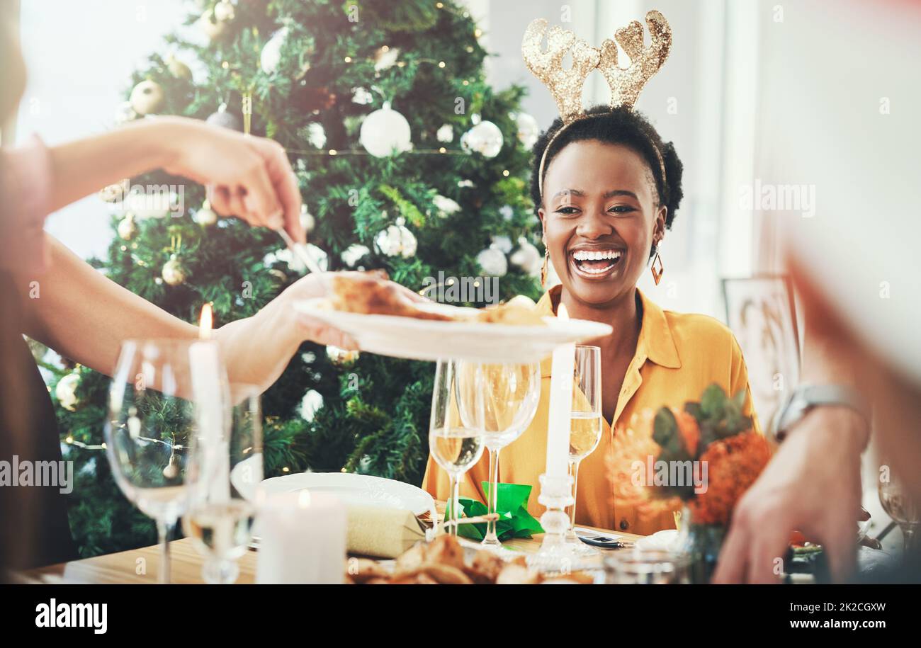 Il suo tempo di mangiare ed essere allegro. Scatto corto di una giovane donna attraente sorridente mentre si fa pranzo di Natale con i suoi amici a casa. Foto Stock