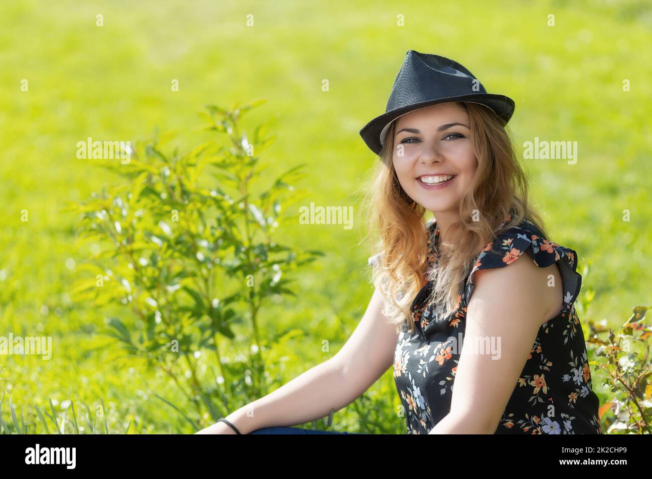 Ritratto di giovane donna sorridente attraente in cappello di paglia che posa all'aperto. Foto Stock