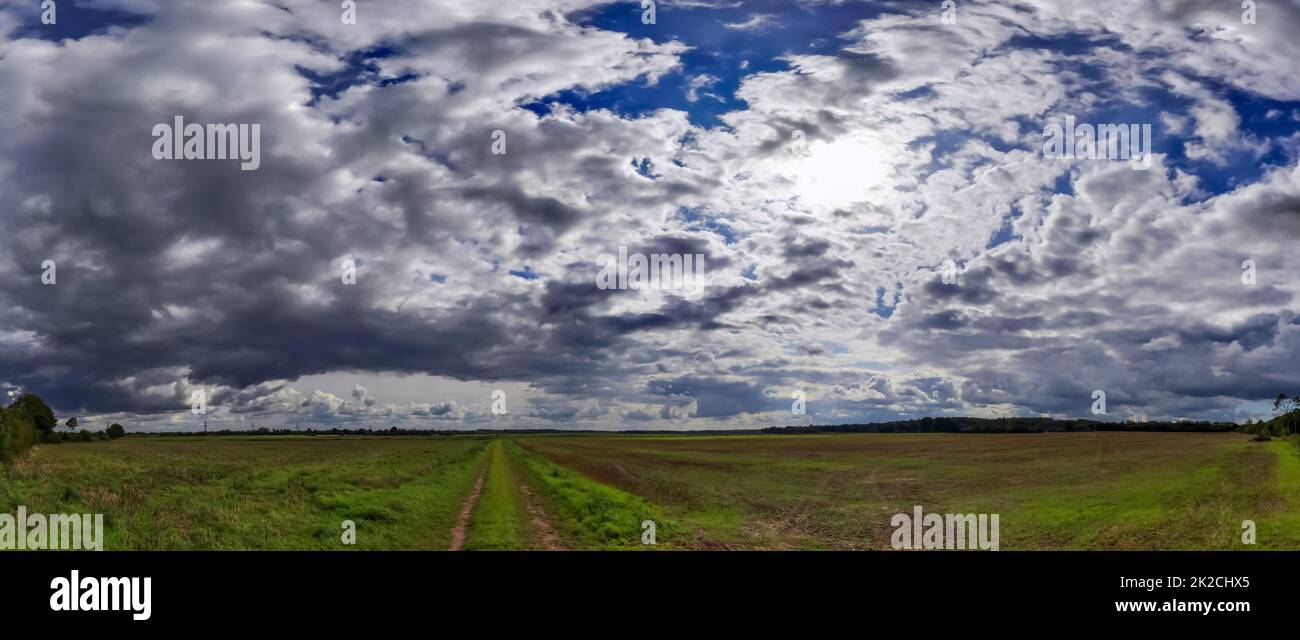 Panorama di nuvole mozzafiato nel cielo sopra un campo agricolo. Foto Stock