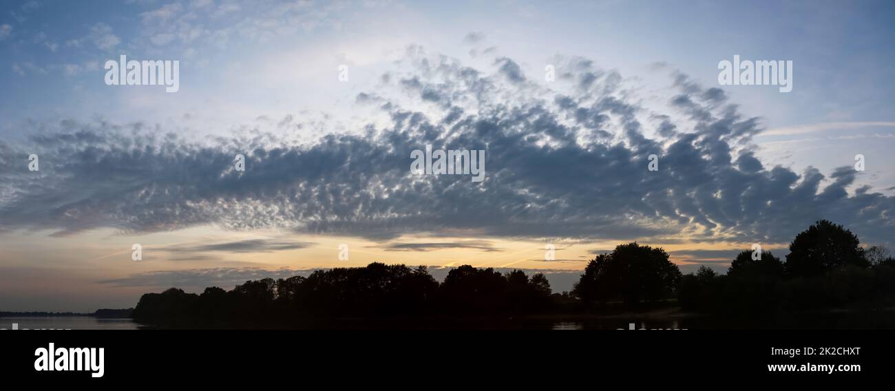 Panorama di nuvole mozzafiato nel cielo sopra un campo agricolo. Foto Stock
