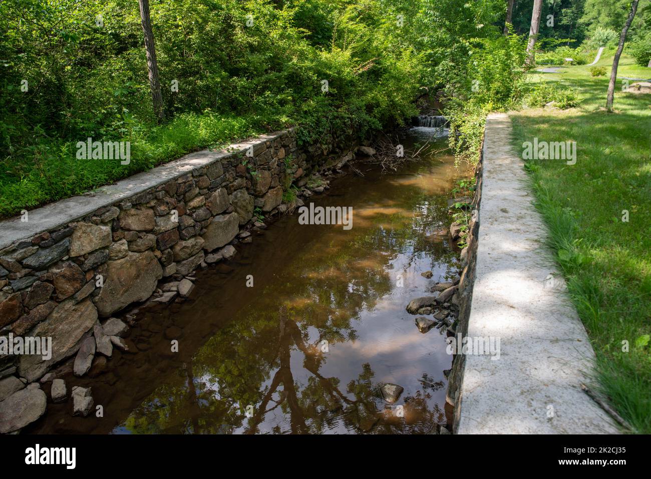 Canale di pietra con acqua fluente tranquilla in verde paesaggio naturale Foto Stock