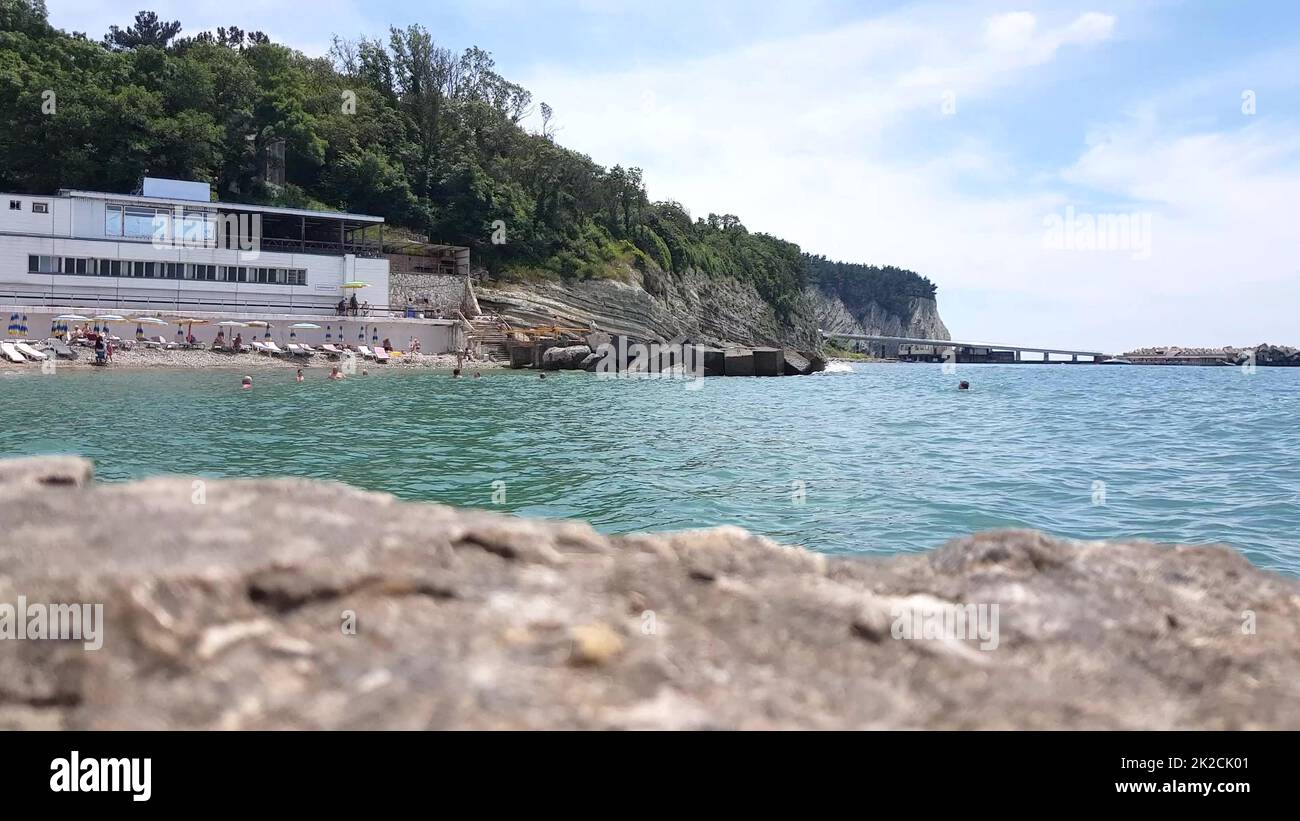 il concetto di una vacanza al mare in un resort, una vista dalla riva di persone a caso che nuotano nel mare Foto Stock