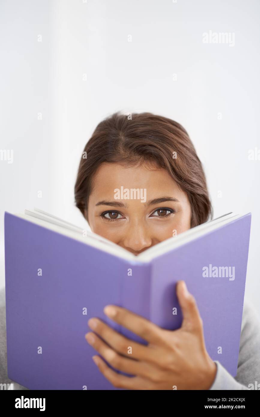 Questa è una lettura interessante. Primo piano di una ragazza sorridente che legge il suo libro. Foto Stock