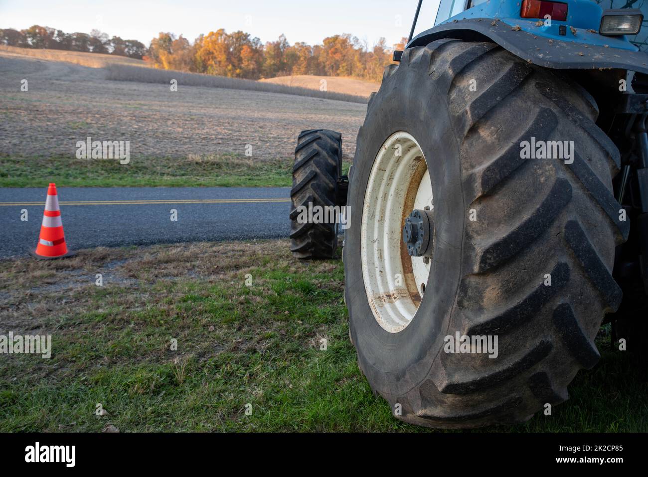 Primo piano del pneumatico blu del trattore con sfondo del campo agricolo Foto Stock