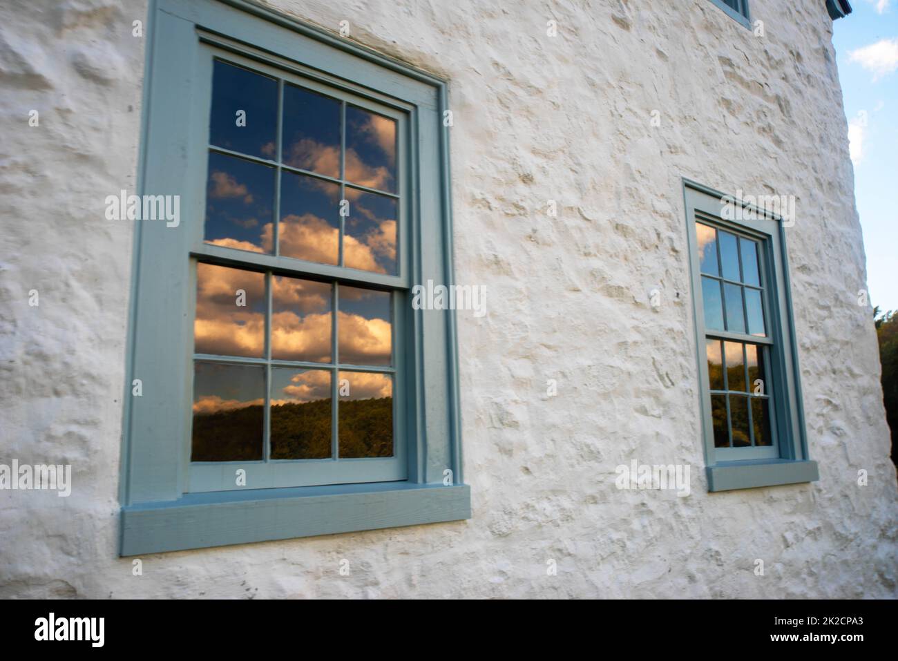 nuvole e cielo blu riflessi in 12-finestre casa coloniale Foto Stock