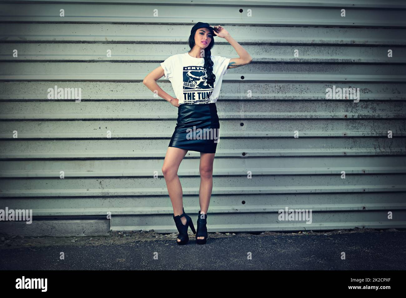 Città ragazza swag. Ritratto di una giovane donna vestita con stile che si erge davanti a una parete metallica. Foto Stock