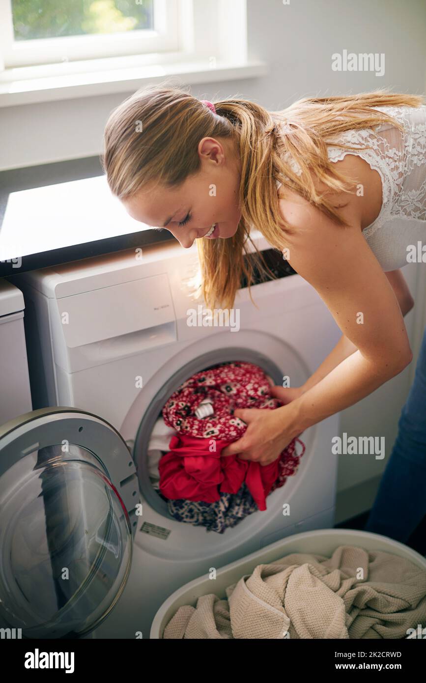 Il suo giorno di lavanderia. Scatto corto della giovane donna che fa il bucato a casa. Foto Stock