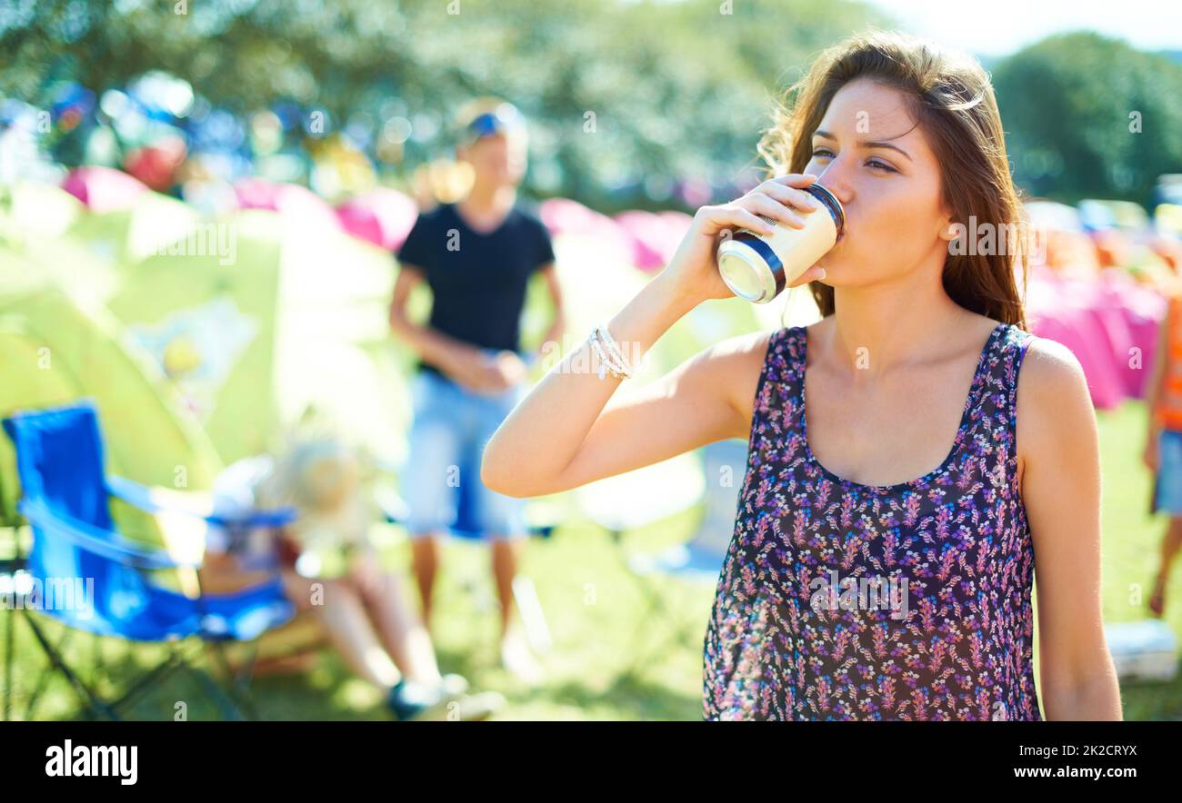 Dissetando. Shot di una giovane donna che beve una lattina di birra in un festival all'aperto. Foto Stock