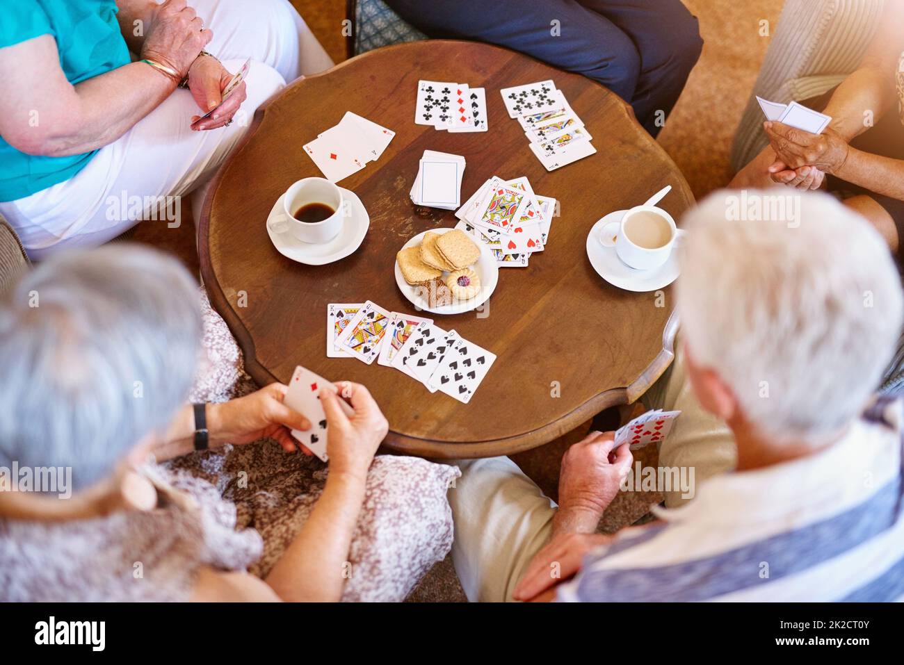 Vincere con una combinazione di fortuna e abilità. Colpo ad angolo alto di un gruppo di anziani che gioca le carte intorno ad un tavolo nella loro casa di pensione. Foto Stock