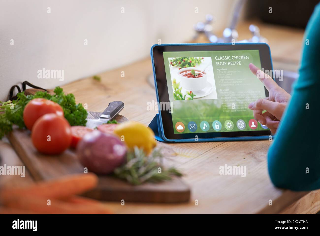 Ooh questo sembra bello.... Scatto corto di una giovane donna che guarda una ricetta online sul suo tablet digitale mentre prepara un pasto. Foto Stock