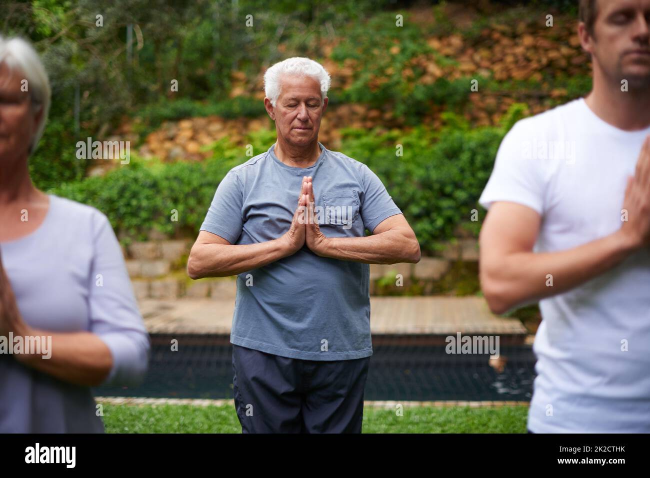 Profondamente legato alla sua spiritualità. Shot di un uomo anziano che medita in una lezione di yoga all'aperto. Foto Stock