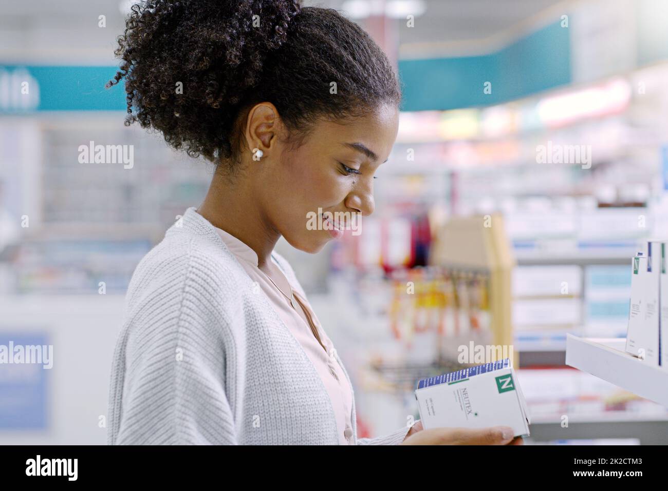Scegliere sempre saggiamente quando si tratta di salute. Primo piano di una giovane donna attraente che legge attraverso il contenuto di un prodotto in una farmacia. Foto Stock