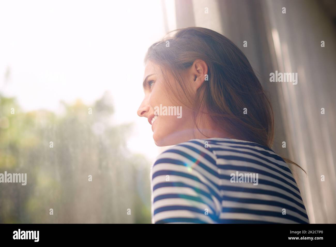 Sarà una bella giornata. Scatto corto di una bella giovane donna bagnata dalla luce della finestra. Foto Stock