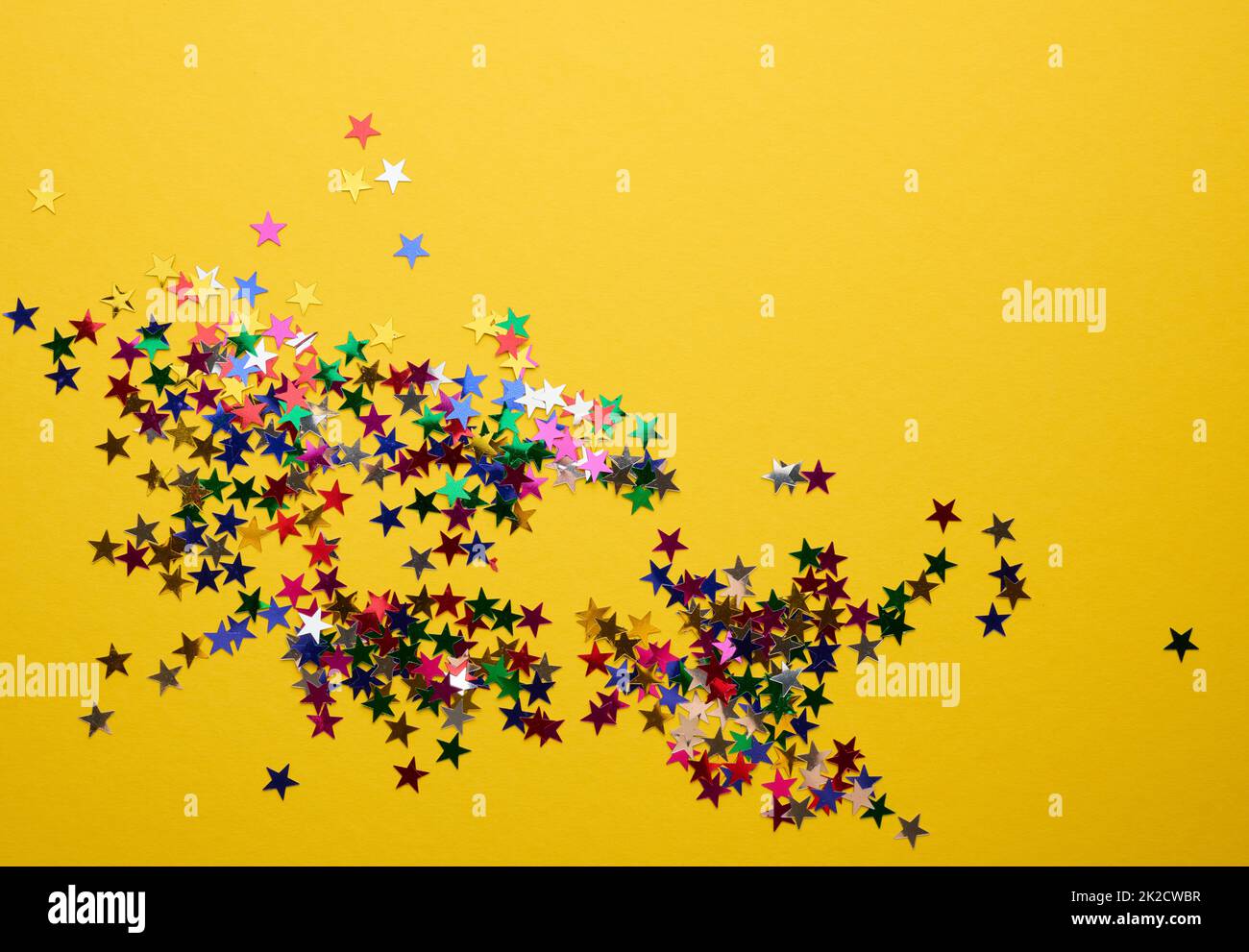 coriandoli di stelle multicolore sparsi su uno sfondo giallo, sfondo festivo per il compleanno, giorno di san valentino. Elemento di decorazione festivo Foto Stock