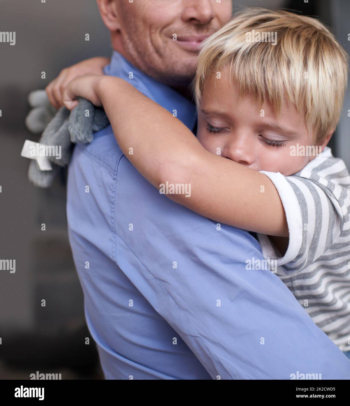 Esaurito dopo una giornata piena di divertimento. Un padre maturo che tornava a casa dal lavoro e abbracciava il ragazzino esausto. Foto Stock