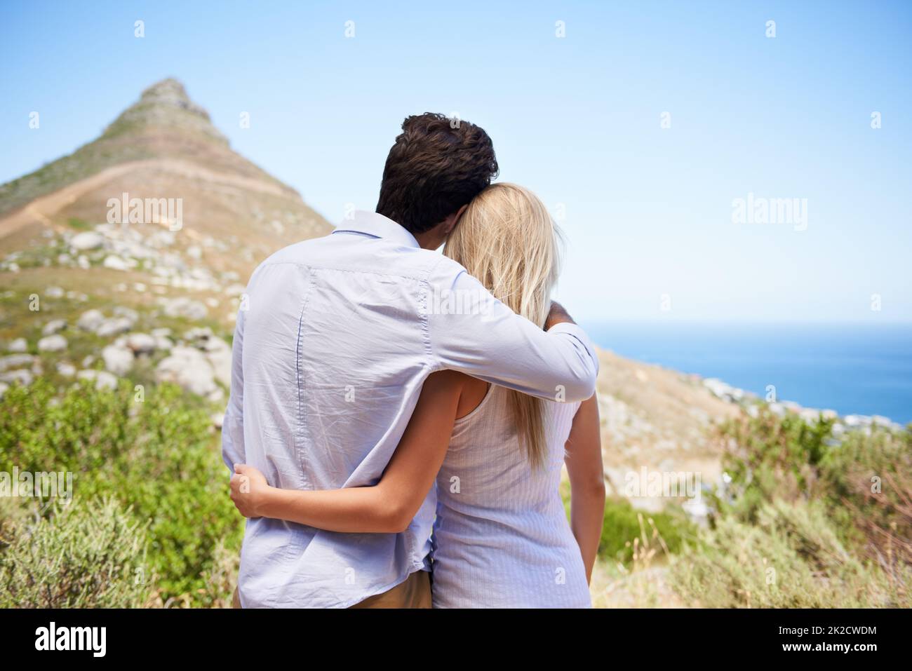 Condivisione di una vista gloriosa. Vista posteriore di una giovane coppia che si abbraccia mentre si gode una vista della montagna. Foto Stock