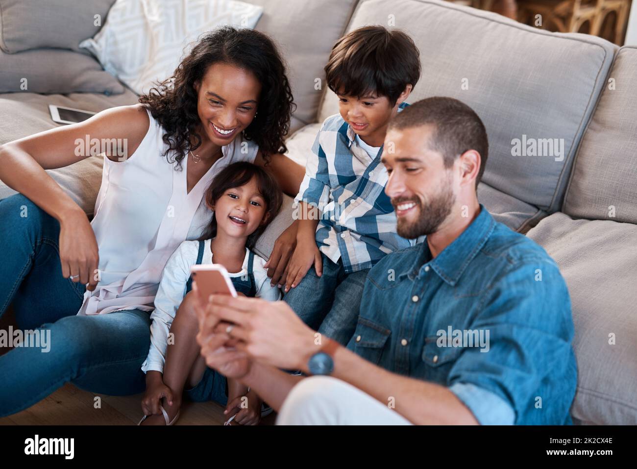 Guardate questo. Scatto di una famiglia di quattro che guarda qualcosa su un cellulare. Foto Stock