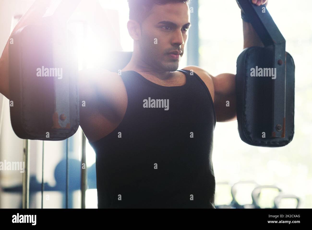 Palestra legata, theres non rinunciare. Scatto corto di un bel giovane sportivo che si allena con una macchina da ginnastica in palestra. Foto Stock