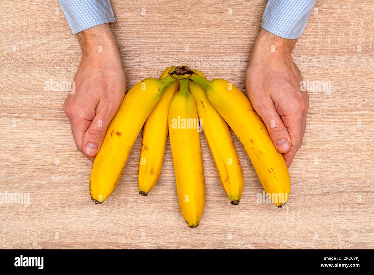 Mani tiene mazzo di Banana fresca sullo sfondo del tavolo Foto Stock