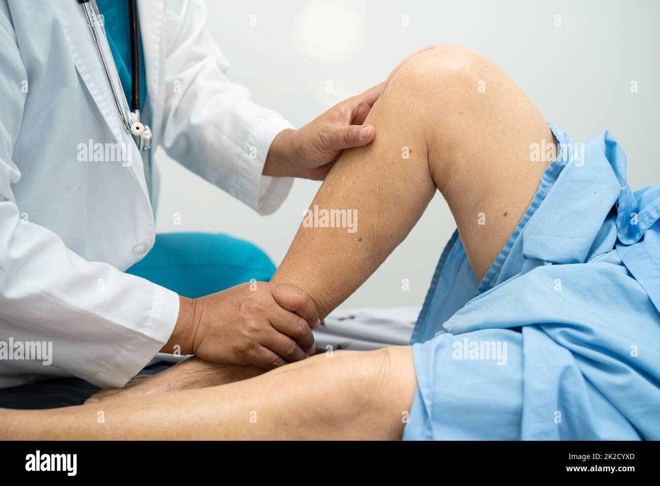 Medico asiatico fisioterapista esame, massaggio e trattamento ginocchio e gamba di paziente anziano in ospedale medico ambulatorio ortopedist infermiere. Foto Stock