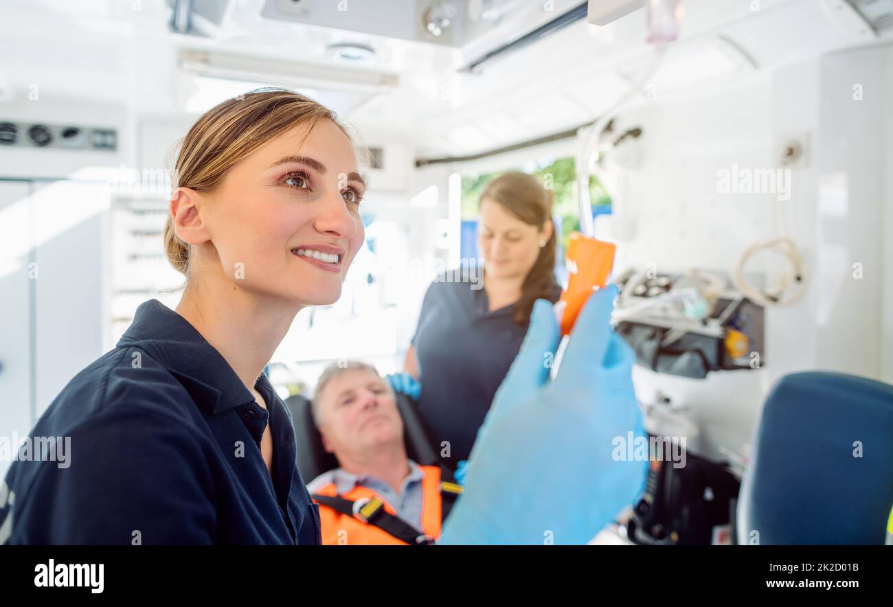 Paramedico che si cura dell'iniezione di goccia in un'ambulanza Foto Stock