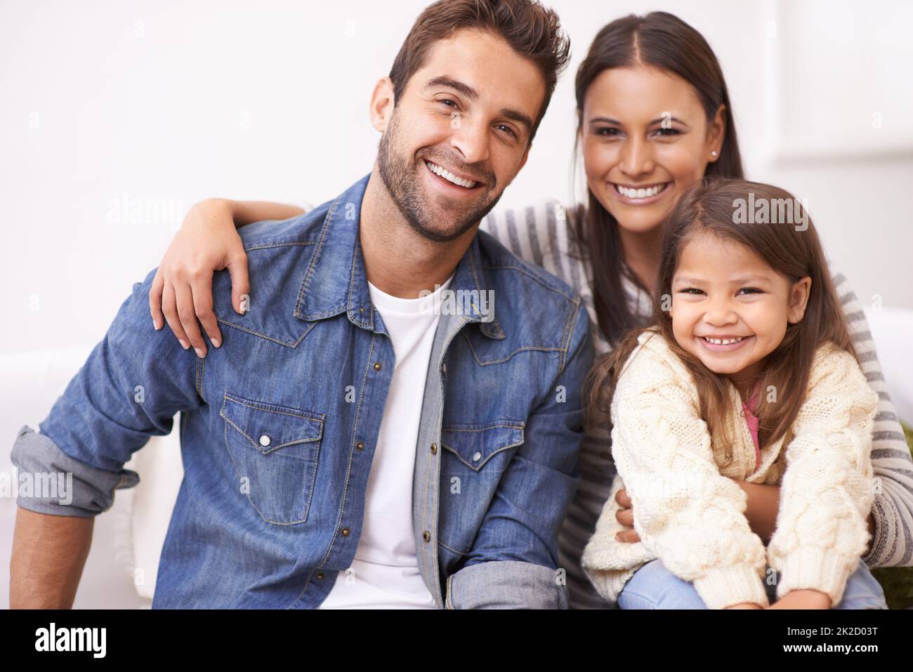Si fanno tesoro. Ritratto di una giovane famiglia felice seduta insieme a casa. Foto Stock
