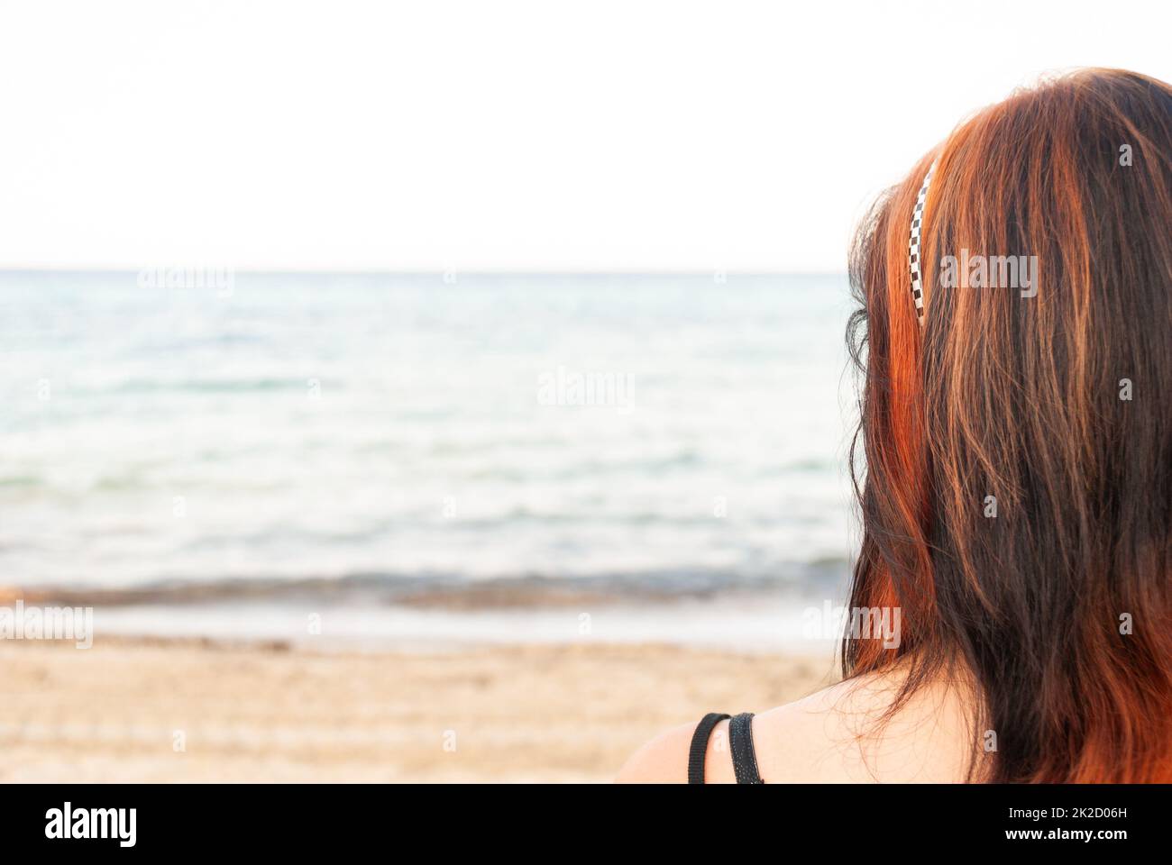 Giovane donna in piedi sulla spiaggia, guardando il mare Foto Stock
