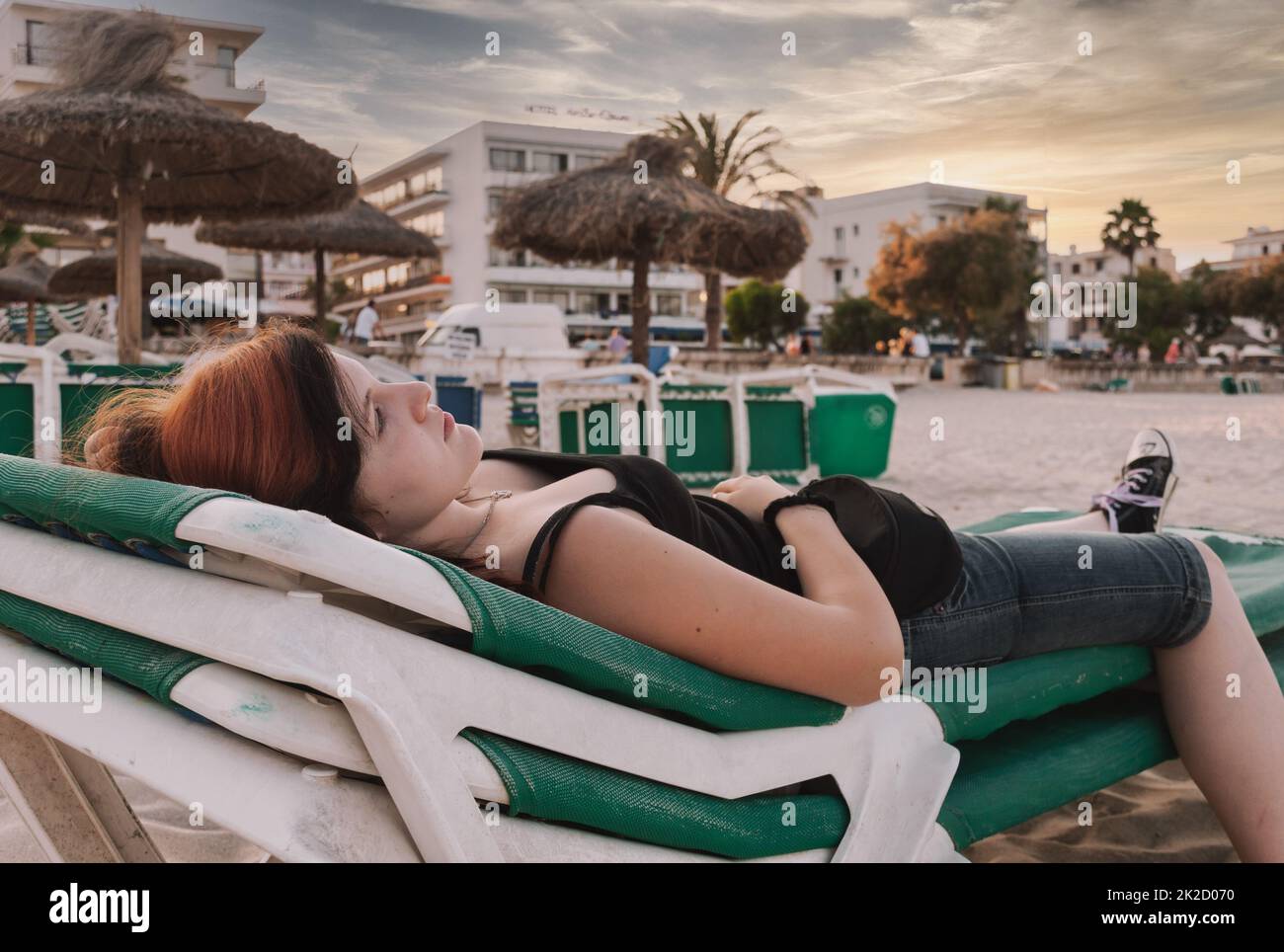 Giovane donna attraente sdraiata su una sedia a sdraio in spiaggia Foto Stock
