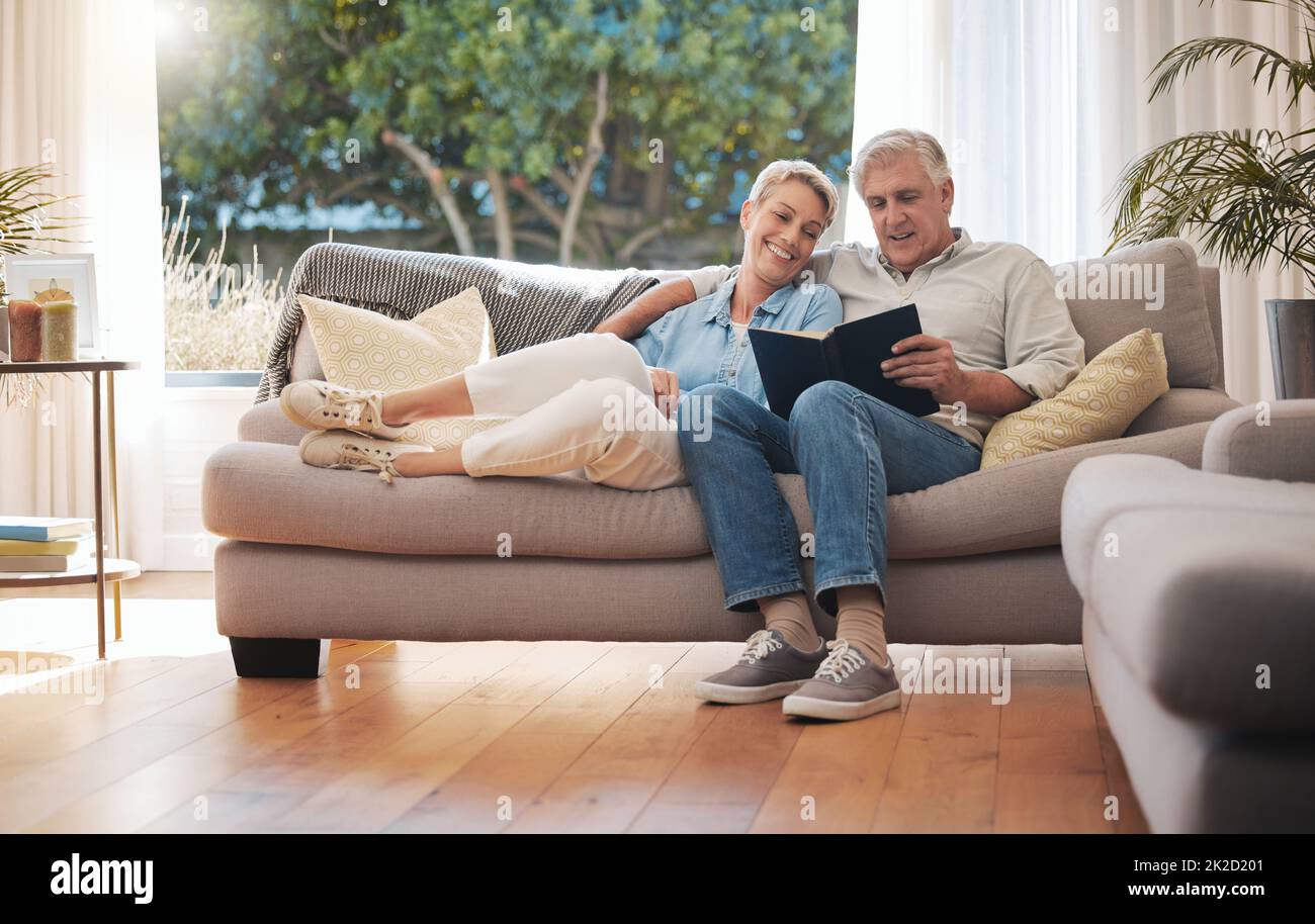Pensione coppia anziana con album fotografico libro sul divano insieme in casa estiva per vacanze. Donna anziana felice o la gente si rilassa sul divano dentro Foto Stock