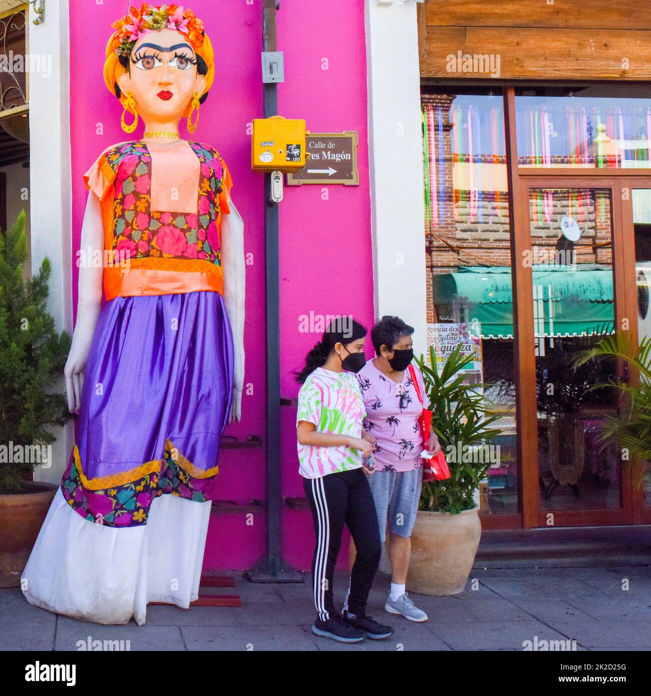 Persone che indossano maschere facciali e una bambola gigante papier mache, nel centro di Oaxaca città, Messico Foto Stock