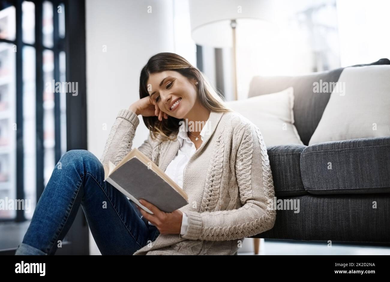 Leggere è la mia cosa preferita da fare nel mio tempo libero. Scatto corto di una bella giovane donna che legge un libro mentre si rilassa a casa. Foto Stock