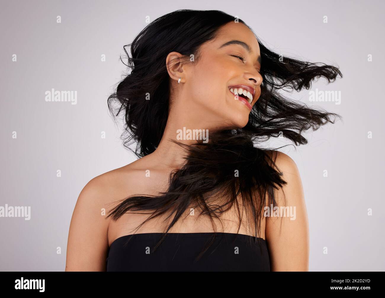 Un buon giorno dei capelli è un buon giorno VOI. Studio girato di una giovane donna scuotendo i capelli mentre si trova su uno sfondo grigio. Foto Stock